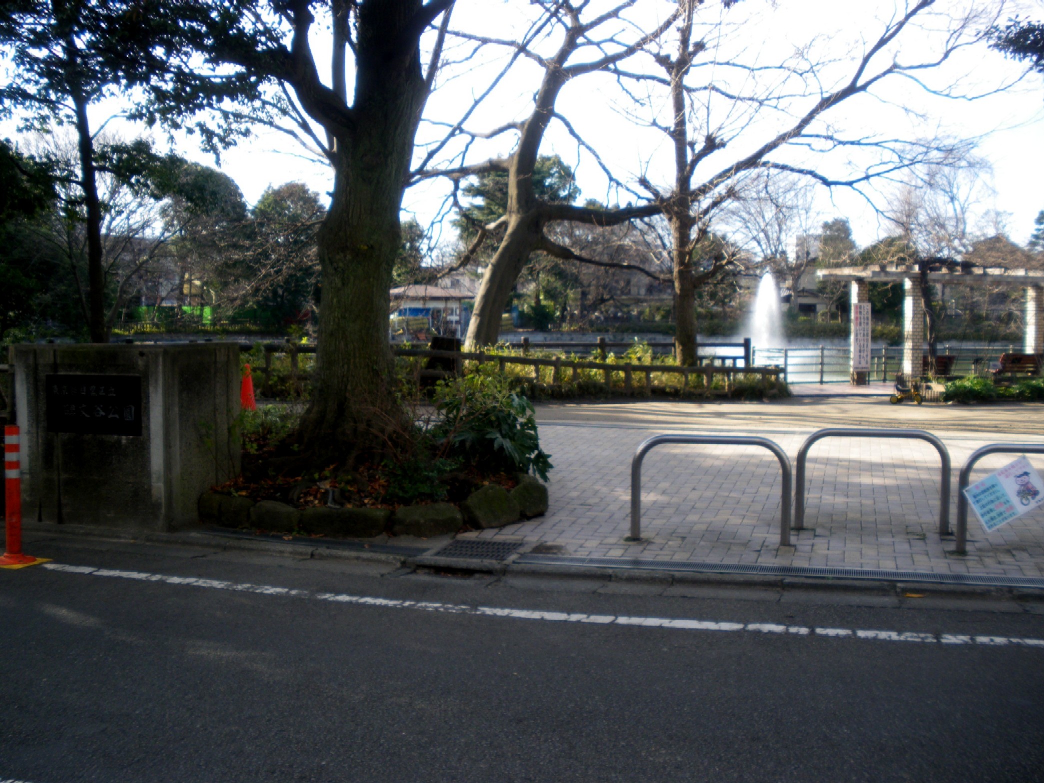 碑文谷公園の石の入口表示と、その奥に広がる池と木々