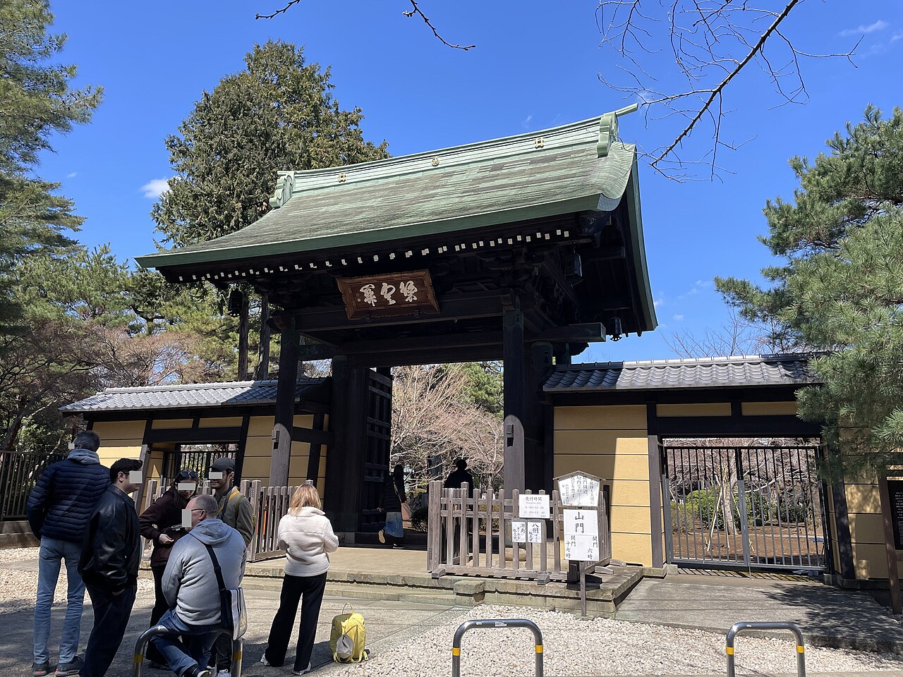 豪徳寺の山門。門の前に参拝者が立っている