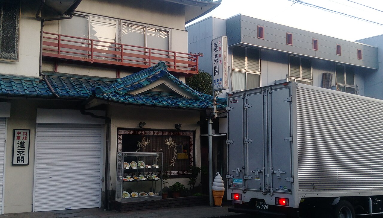 長谷の通りに並ぶ小規模な店舗と、その前を通る車