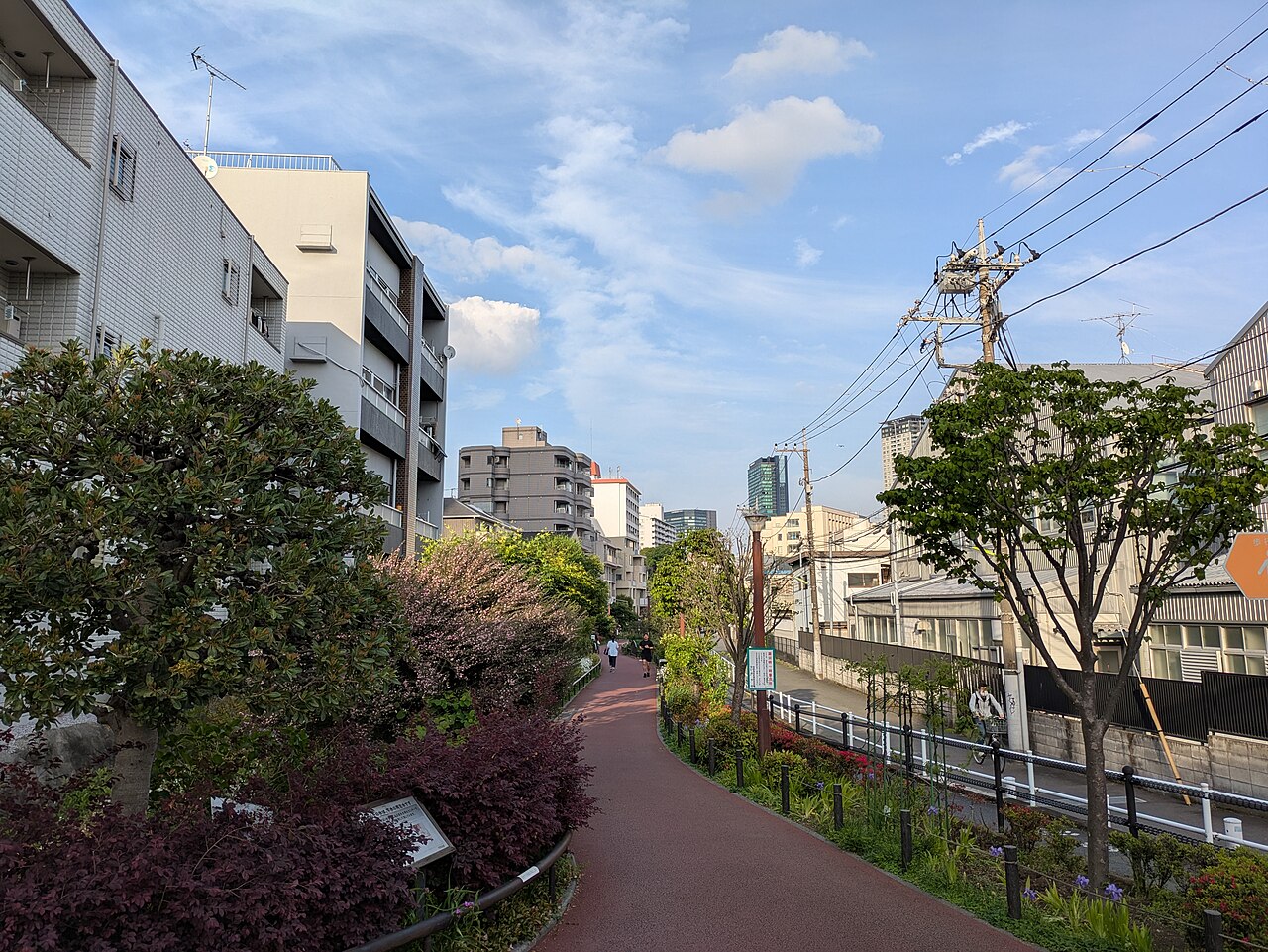池尻の目黒川緑道。住宅の間を曲がる歩行空間と植栽が見える。