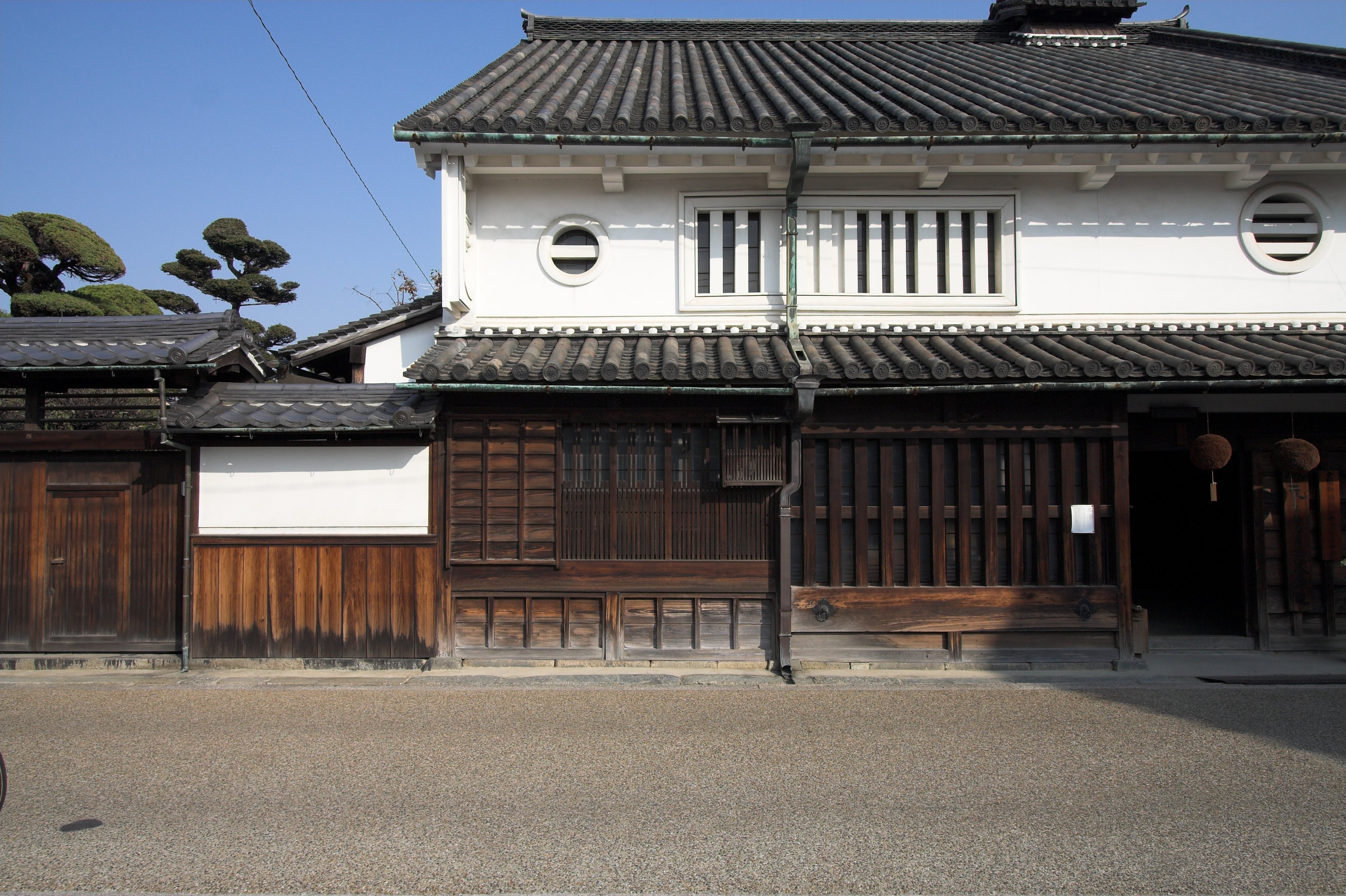 二階の白壁に丸窓があり一階に木の格子が並ぶ、今井町の河合家住宅