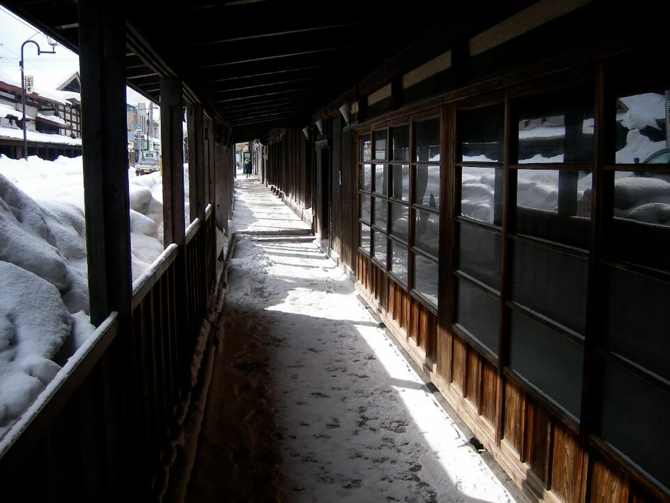 道路側に雪が積もり庇の下に通路が残る冬のこみせ