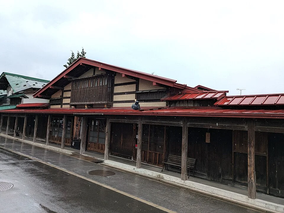 赤い屋根と木造のこみせを持つ高橋家住宅の外観