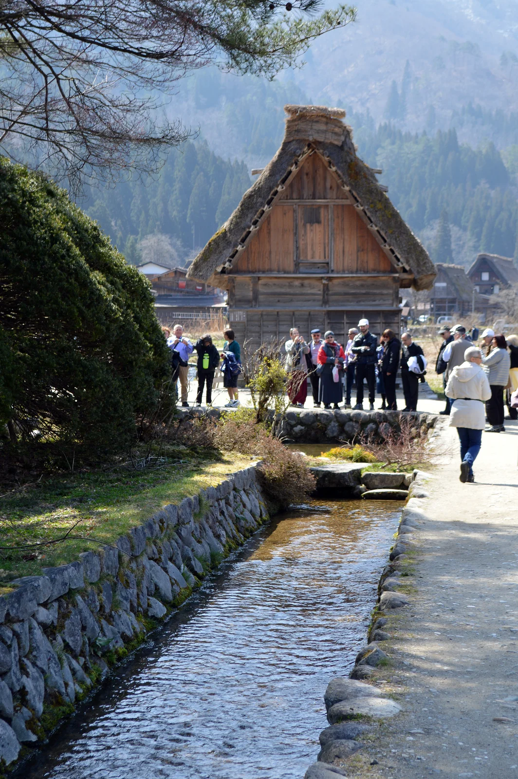 石積みの水路と、そのそばの道や茅葺きの建物