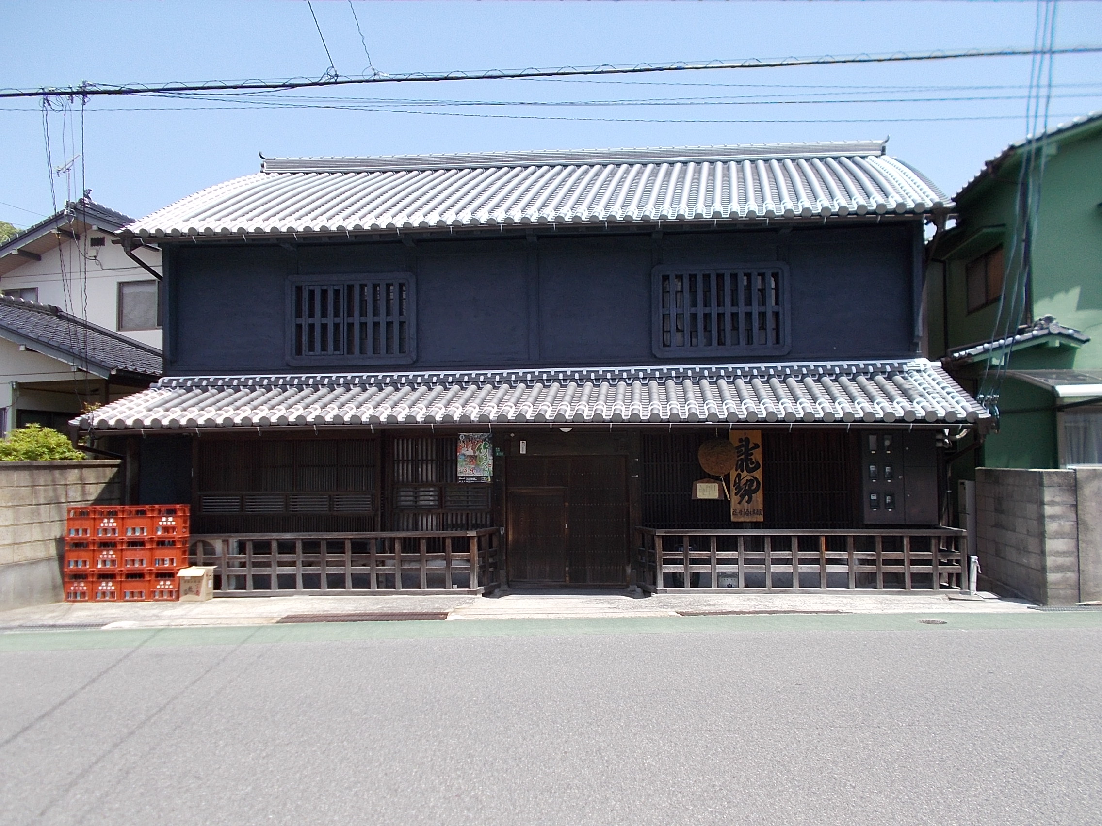 藤井酒造の外観。黒い壁の建物に龍勢の看板と杉玉が掛かる