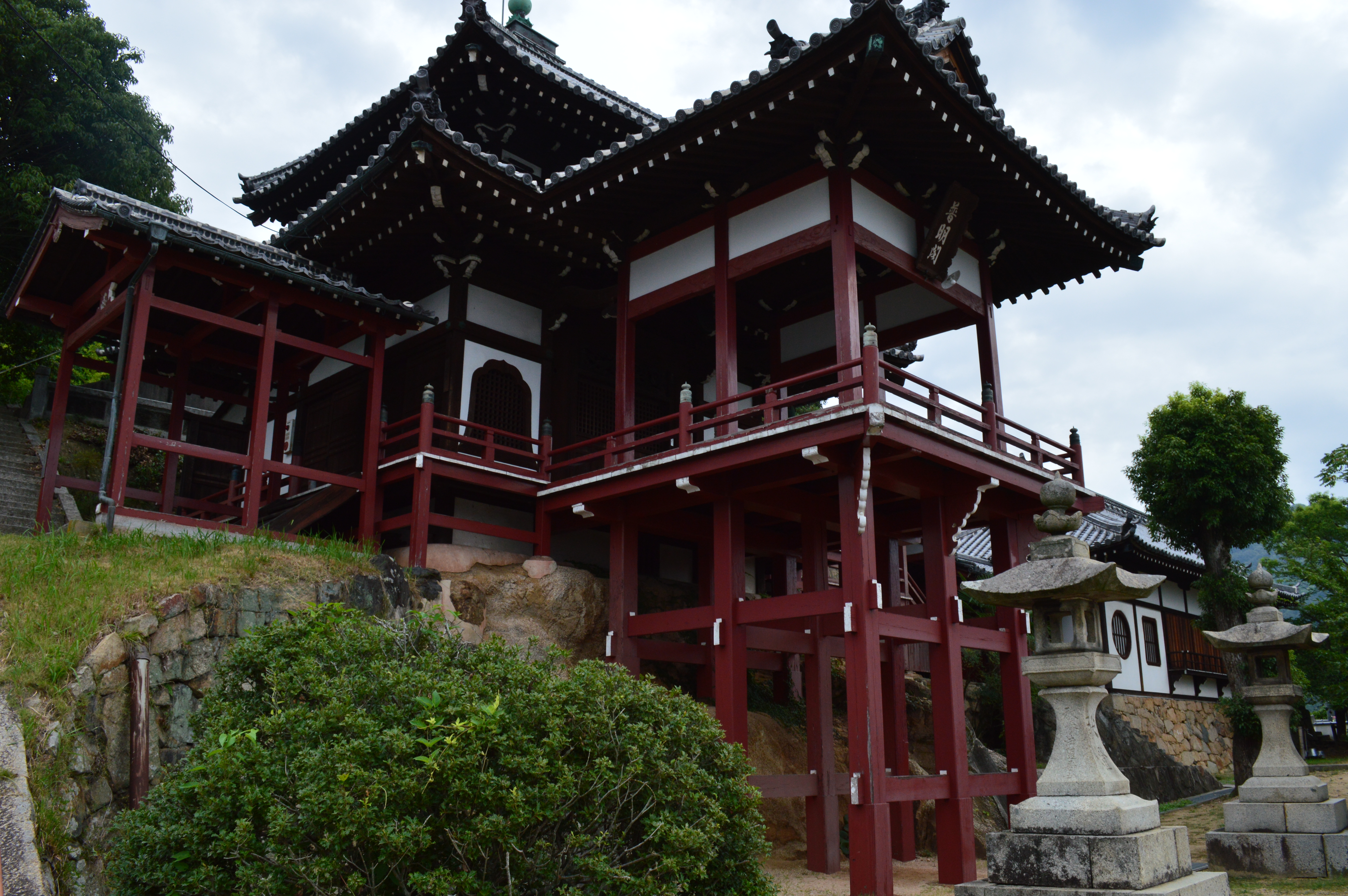 斜面に柱を立てて建つ西方寺の普明閣。赤い柱と重なる屋根が見える