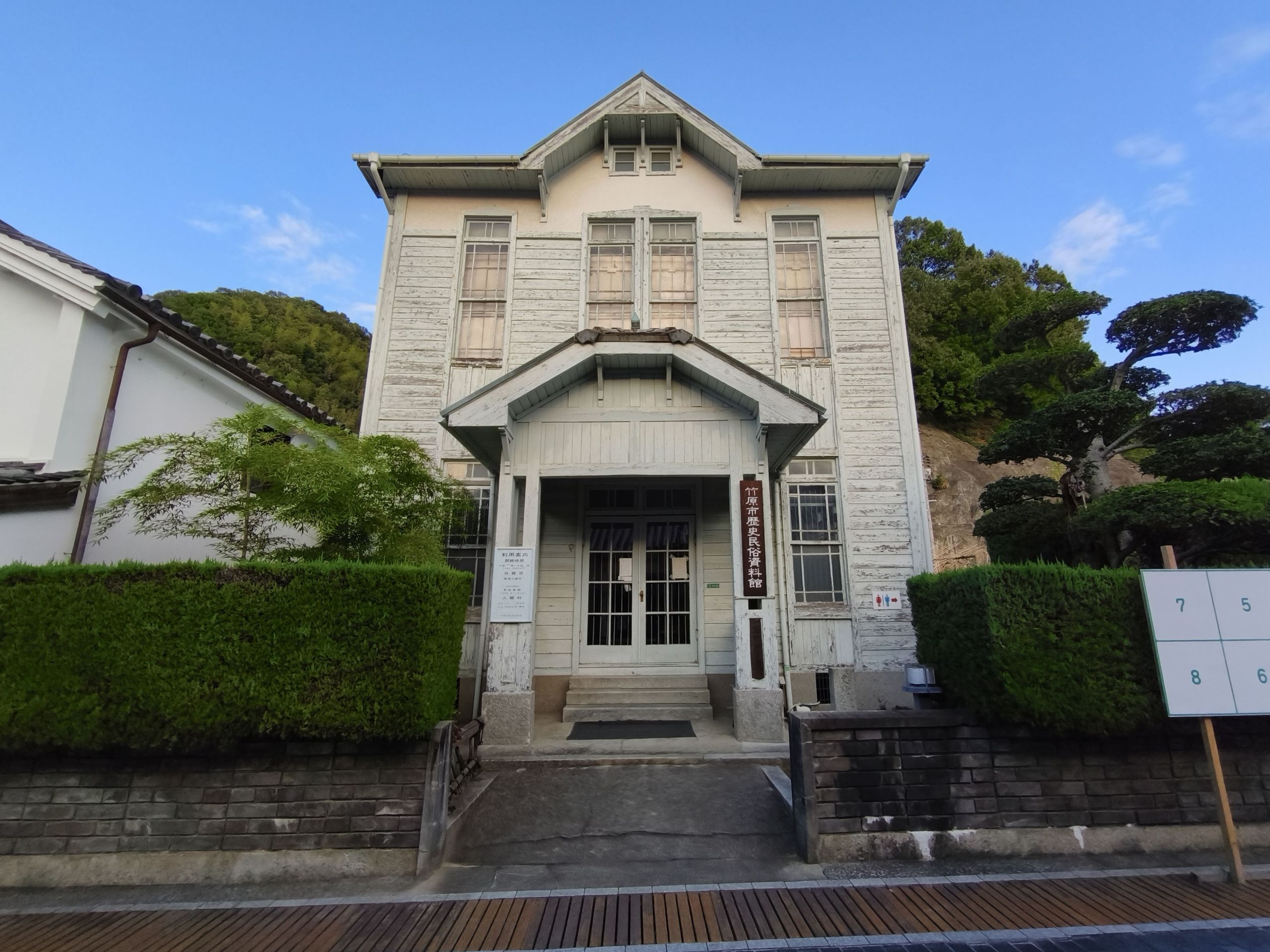 竹原市歴史民俗資料館の白い木造建築。中央に玄関と三角形の屋根がある