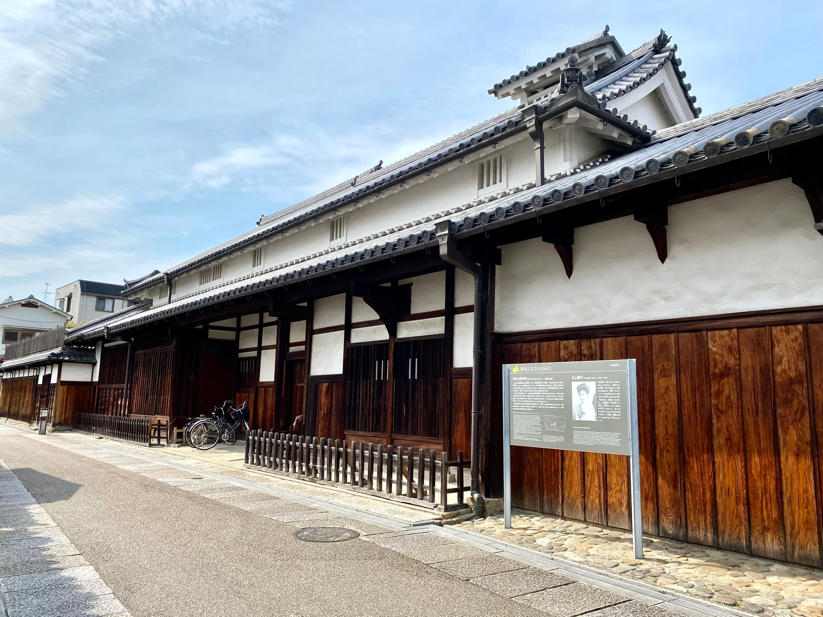 通りに沿って大きな瓦屋根と長い木の格子が続く旧杉山家住宅
