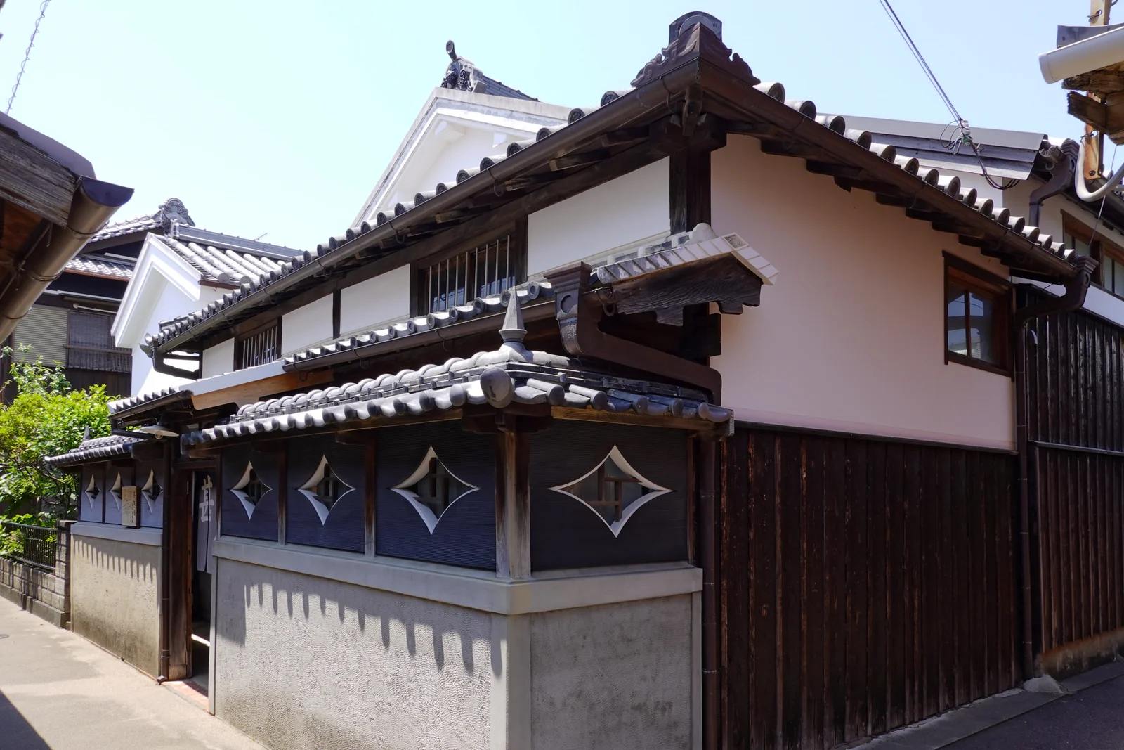 ひし形の開口部が並ぶ甚風呂の外壁と瓦屋根